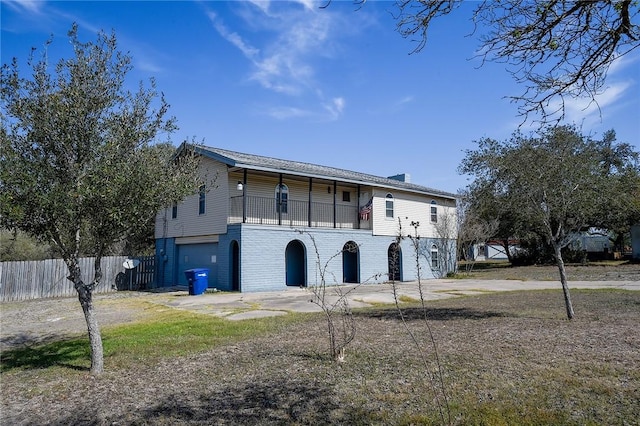 view of side of home with brick siding, driveway, a garage, and fence