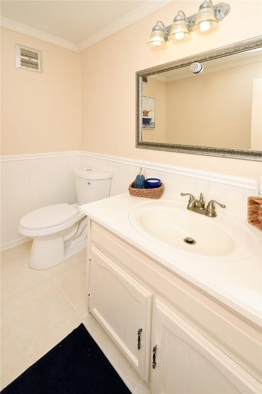 bathroom with visible vents, crown molding, a wainscoted wall, toilet, and vanity