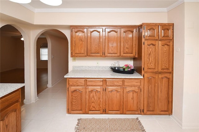 kitchen with light countertops, light tile patterned flooring, brown cabinets, and ornamental molding