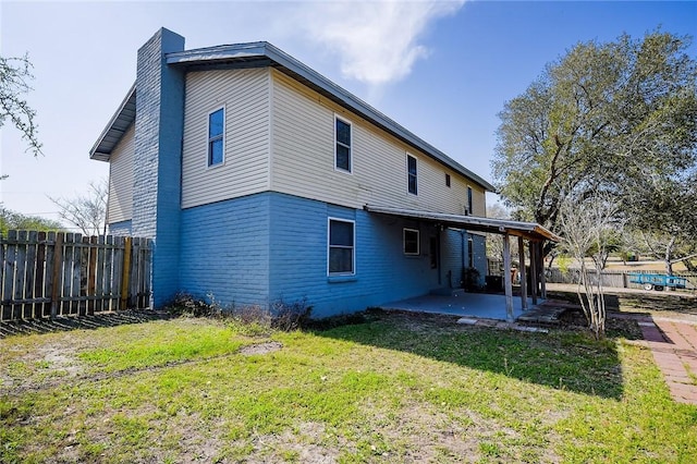 rear view of house with a yard, an attached carport, a fenced backyard, and a patio area