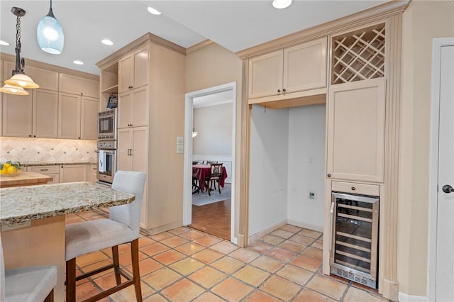 kitchen featuring wine cooler, tasteful backsplash, hanging light fixtures, stainless steel appliances, and light stone countertops