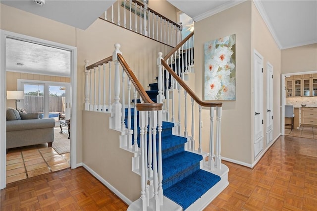 stairway featuring crown molding and parquet floors