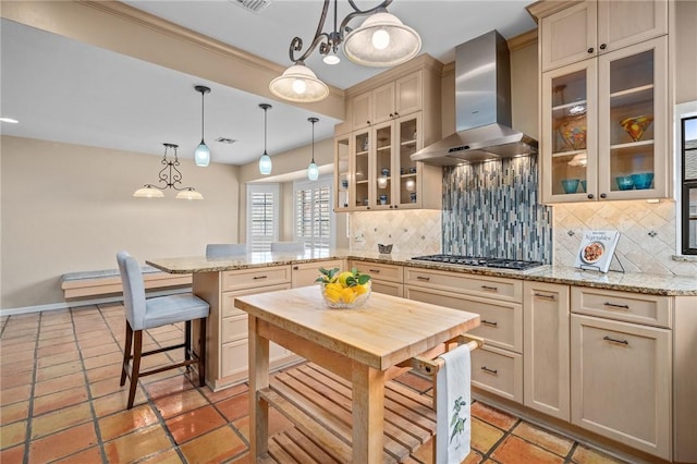 kitchen featuring tasteful backsplash, hanging light fixtures, stainless steel gas stovetop, and wall chimney exhaust hood