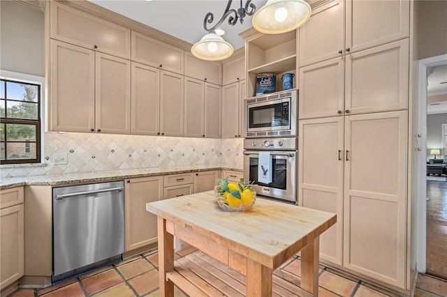 kitchen featuring tasteful backsplash, light stone countertops, appliances with stainless steel finishes, and pendant lighting