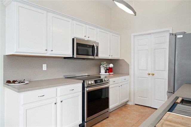 139 Heron Oaks St, Rockport, TX 78382 - kitchen featuring appliances with stainless steel finishes, light countertops, white cabinets, and light tile patterned floors