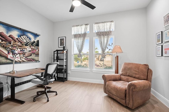 office area with baseboards, light wood-style floors, and ceiling fan