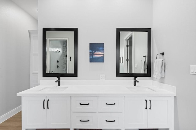 bathroom with double vanity, a sink, and wood finished floors