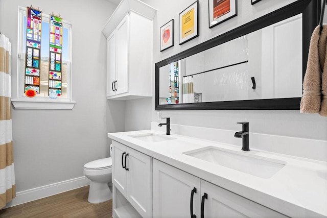 full bathroom featuring a sink, baseboards, toilet, and wood finished floors