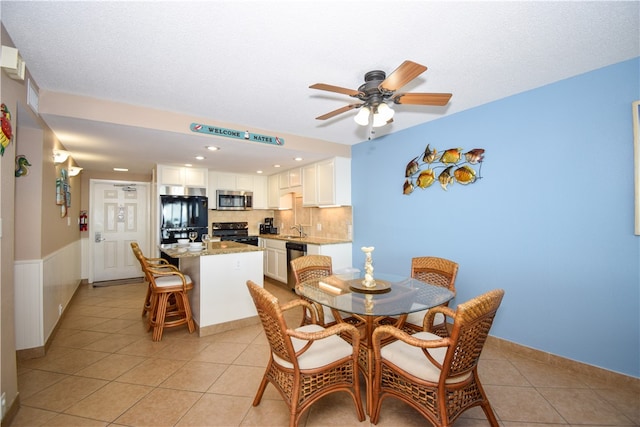 tiled dining space with ceiling fan and sink