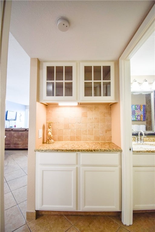 bar featuring light tile patterned flooring, light stone countertops, sink, and tasteful backsplash