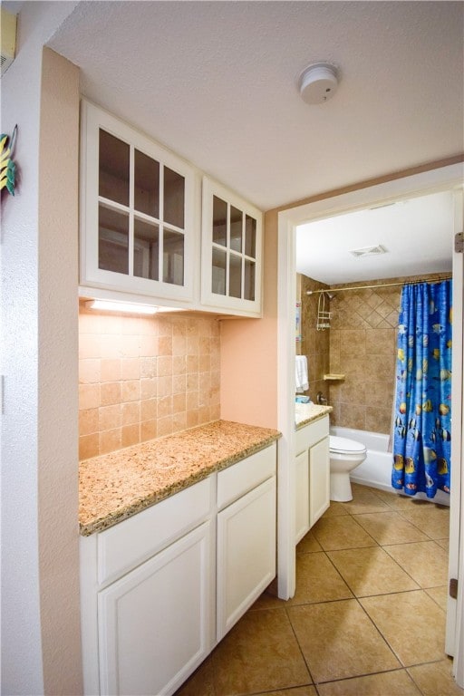 full bathroom with tile patterned flooring, shower / bath combo with shower curtain, vanity, toilet, and decorative backsplash