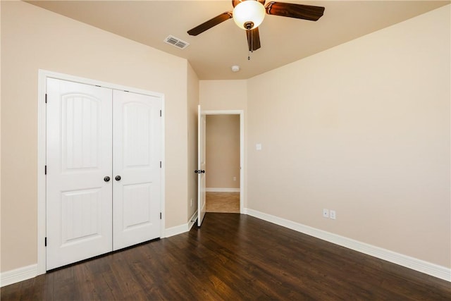 unfurnished bedroom with dark wood-style floors, visible vents, baseboards, ceiling fan, and a closet