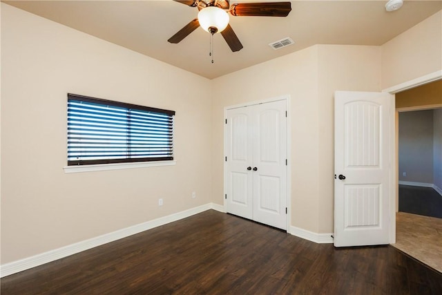 unfurnished bedroom featuring a ceiling fan, baseboards, visible vents, dark wood finished floors, and a closet