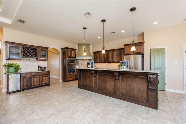 kitchen with visible vents, dark brown cabinetry, custom exhaust hood, arched walkways, and stainless steel appliances