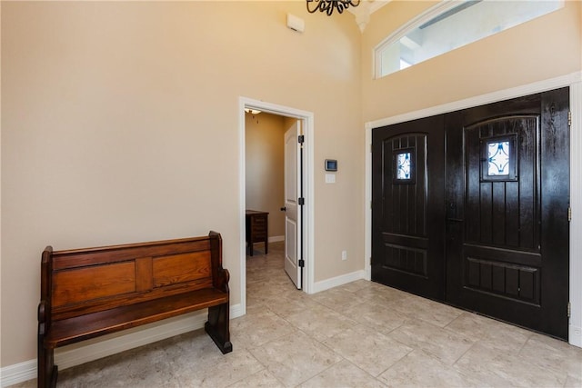 entrance foyer with baseboards and a towering ceiling