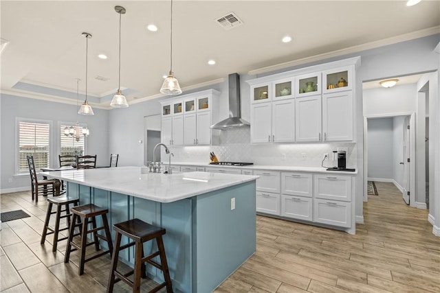 kitchen with ornamental molding, visible vents, wall chimney range hood, and decorative backsplash