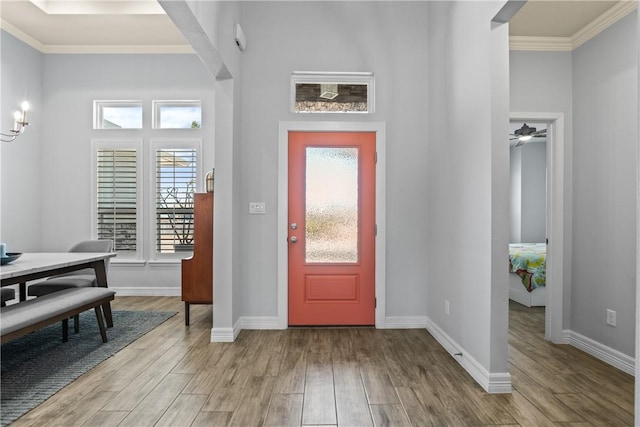 foyer entrance featuring a wealth of natural light, wood finished floors, and ornamental molding