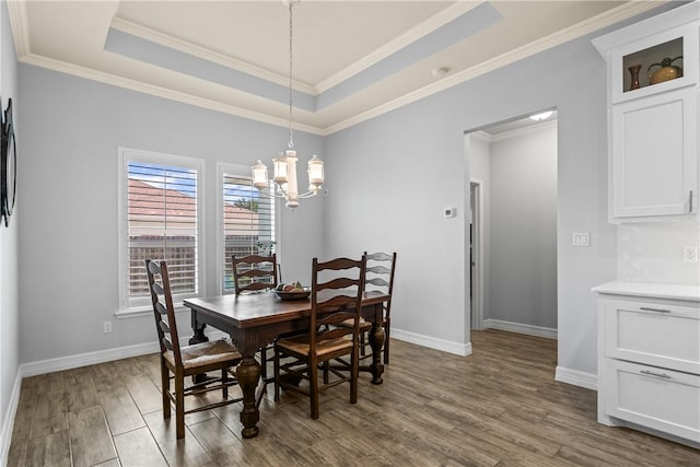 dining room with a chandelier, baseboards, wood finished floors, and a raised ceiling