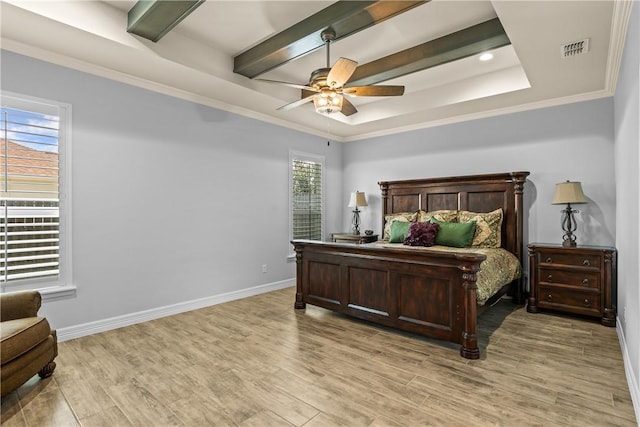 bedroom featuring light wood finished floors, visible vents, baseboards, and a tray ceiling