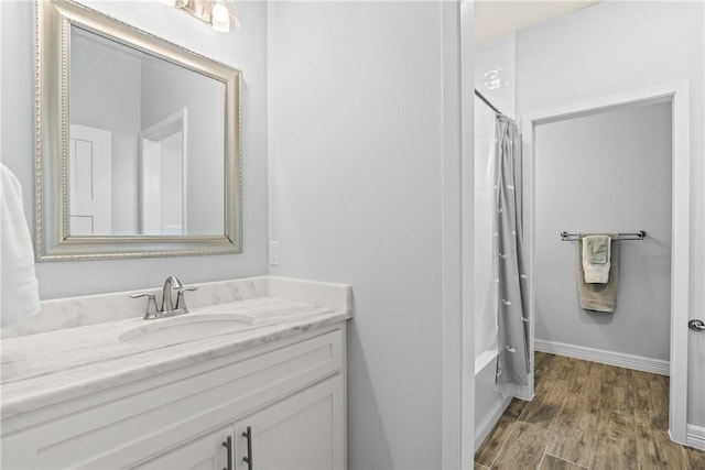 full bathroom featuring shower / tub combo, wood finished floors, vanity, and baseboards