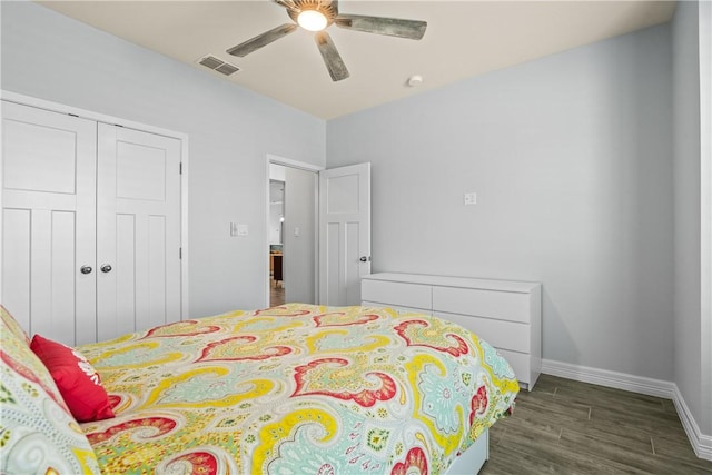 bedroom featuring wood finished floors, a closet, baseboards, visible vents, and a ceiling fan