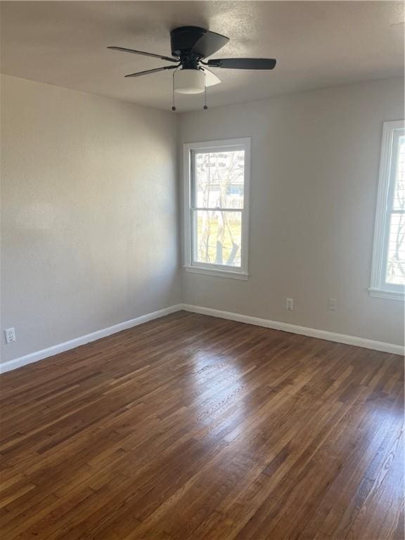 empty room with ceiling fan, baseboards, and dark wood-style flooring