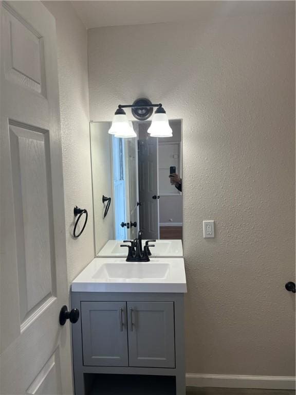 bathroom with a textured wall, vanity, and baseboards