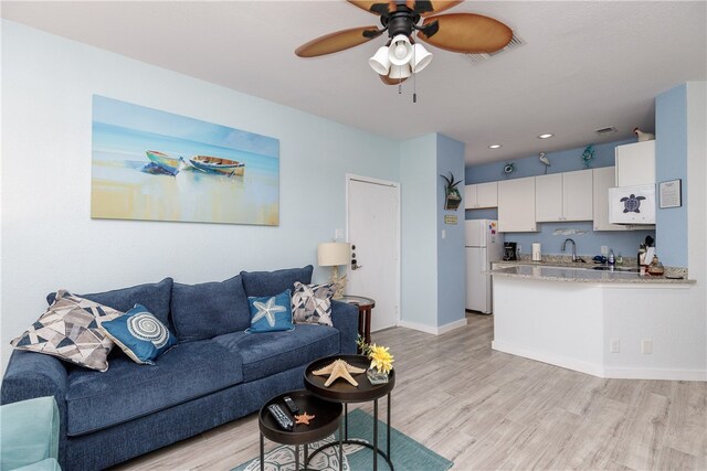 living room featuring ceiling fan, sink, and light hardwood / wood-style floors