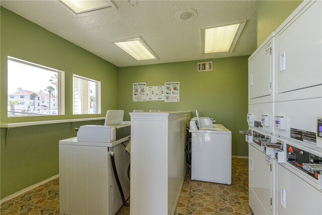 washroom with a textured ceiling, stacked washer / drying machine, and washing machine and clothes dryer