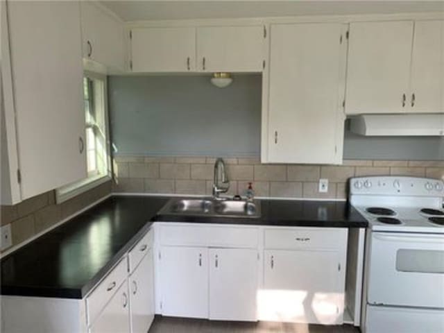 kitchen with electric range, dark countertops, and a sink