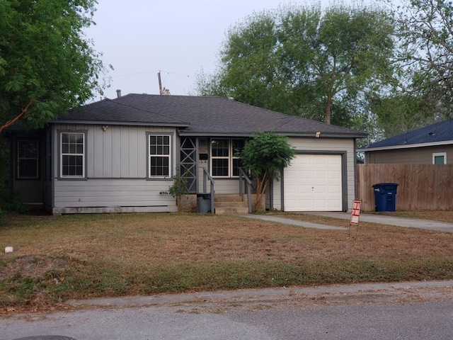 ranch-style home with driveway, fence, a front lawn, an attached garage, and a shingled roof
