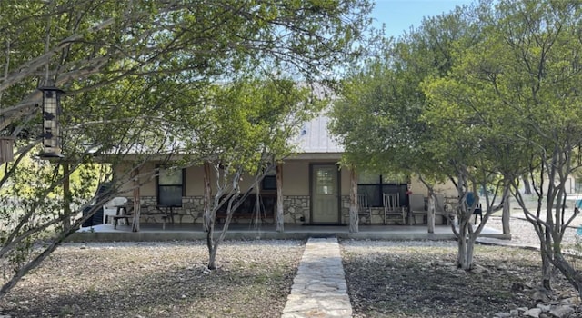 197 N Tomahawk Way, Concan, TX 78838 - view of property hidden behind natural elements featuring a porch, stucco siding, and stone siding