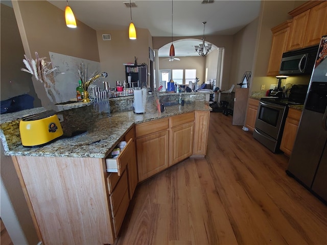 kitchen with appliances with stainless steel finishes, ceiling fan with notable chandelier, a large island with sink, and light hardwood / wood-style flooring