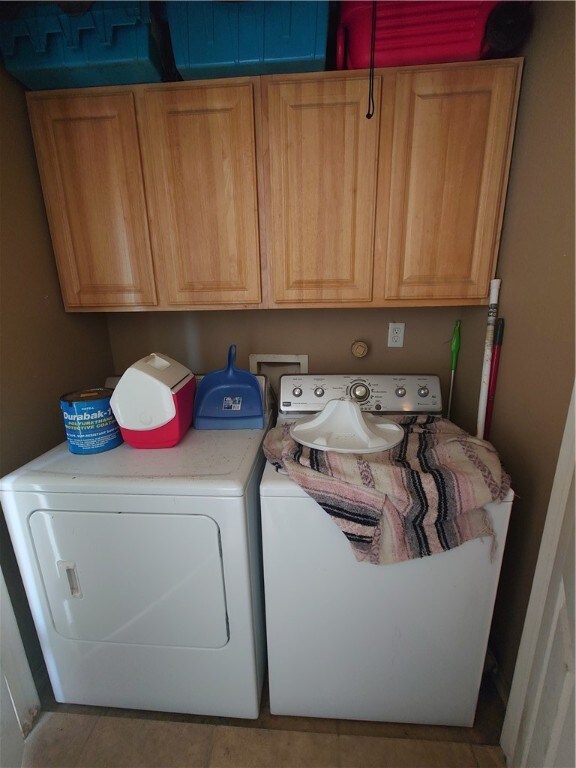 washroom with cabinets, light tile patterned floors, and washer and clothes dryer