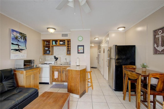 3938 Surfside Blvd Unit 3114, Corpus Christi, TX 78402 - kitchen with appliances with stainless steel finishes, a kitchen bar, light tile patterned floors, ornamental molding, and ceiling fan