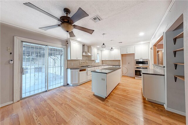 445 Troy Dr, Corpus Christi, TX 78412 - kitchen with wall chimney range hood, dark countertops, appliances with stainless steel finishes, decorative backsplash, and light wood-style floors