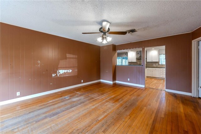 445 Troy Dr, Corpus Christi, TX 78412 - empty room featuring light wood-style flooring, a ceiling fan, a textured ceiling, wooden walls, and baseboards