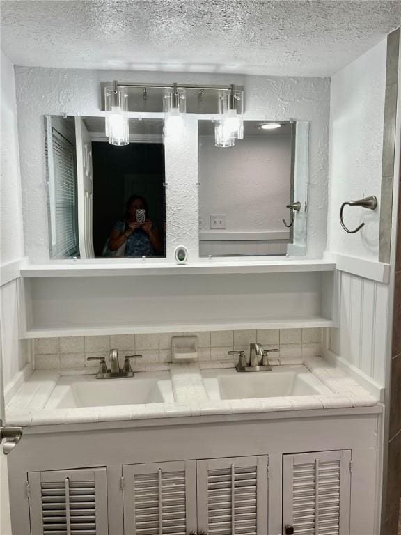 4225 Lowman St, Corpus Christi, TX 78411 - bathroom with a textured ceiling, double vanity, a textured wall, and backsplash
