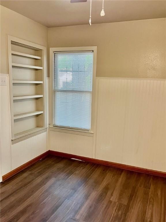 4225 Lowman St, Corpus Christi, TX 78411 - spare room featuring dark wood-style flooring, a wainscoted wall, and built in shelves