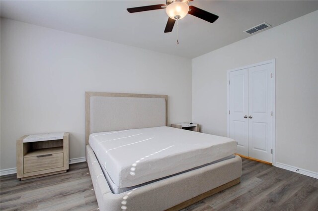 bedroom with a closet, hardwood / wood-style flooring, and ceiling fan