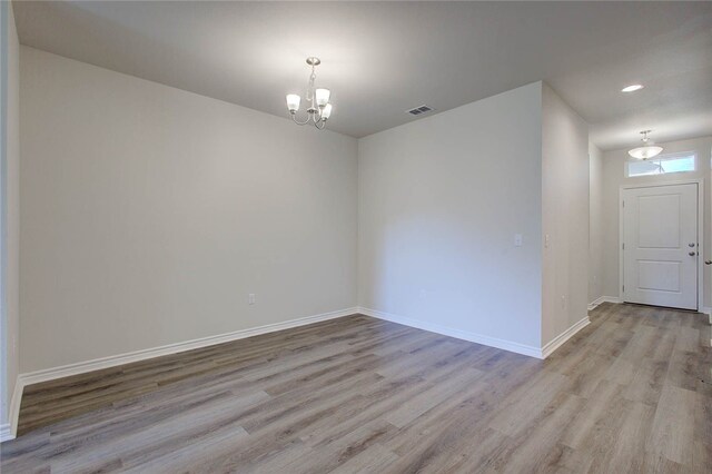 unfurnished room with light hardwood / wood-style floors and a chandelier