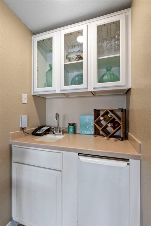 bar featuring white cabinets, stainless steel dishwasher, and sink