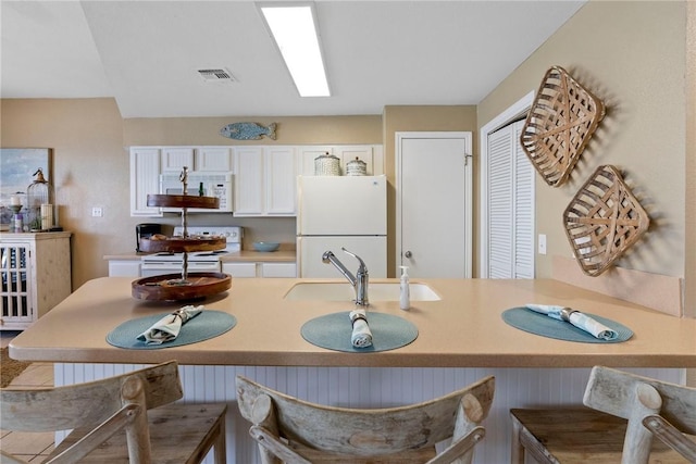 6317 State Highway 361 Unit 6203, Port Aransas, TX 78373 - kitchen featuring white appliances, white cabinetry, a kitchen breakfast bar, light countertops, and a peninsula