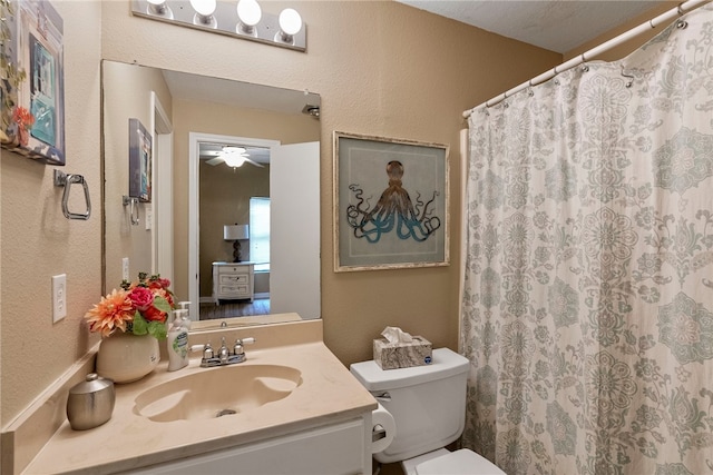 bathroom featuring curtained shower, ceiling fan, vanity, and toilet