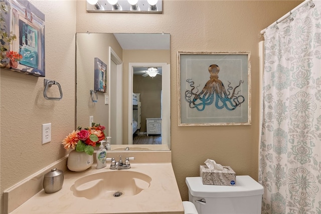 bathroom featuring toilet, sink, and ceiling fan