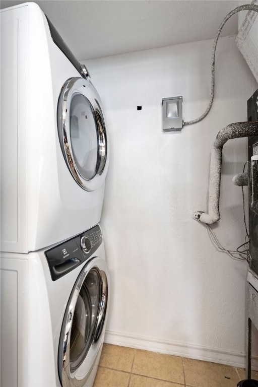 laundry room featuring stacked washer and dryer and light tile patterned flooring