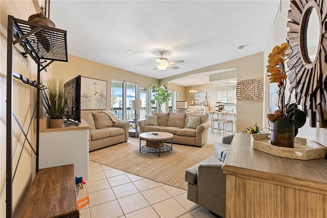 tiled living room featuring ceiling fan with notable chandelier