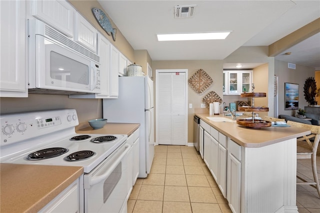 kitchen featuring light tile patterned flooring, white cabinetry, kitchen peninsula, sink, and white appliances