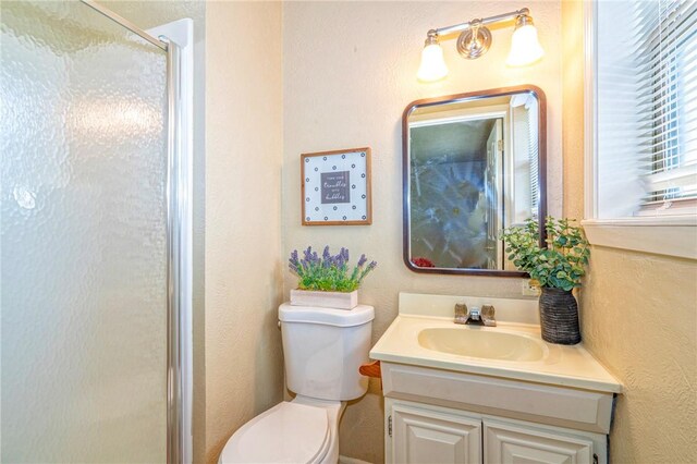 full bathroom featuring a textured wall, vanity, a shower stall, and toilet