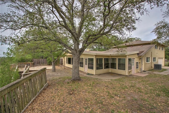 back of property with roof with shingles, central air condition unit, fence, a garage, and a sunroom